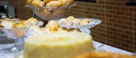 A table with various food items including a large cake and several bowls of pastries.
