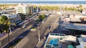 A coastal road with buildings, a pool area, and a view of the beach. - Rede Andrade Araras (Aracaju)