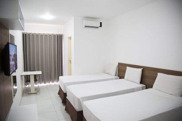 A hotel room with two beds, a TV, a table, and a curtain. - Rede Andrade Araras (Aracaju)