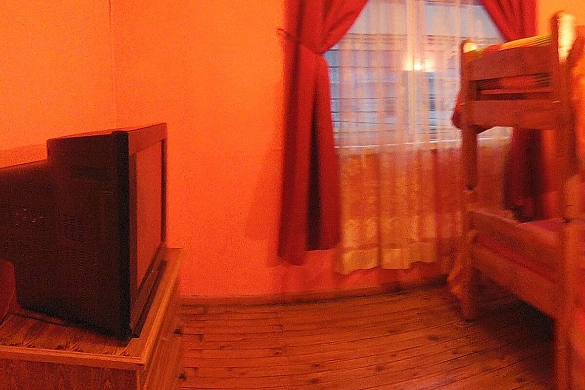 A room with a bunk bed, a desk, and a television.