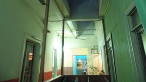 Un pasillo estrecho con tragaluz, una puerta que da a otra habitación y una escalera.