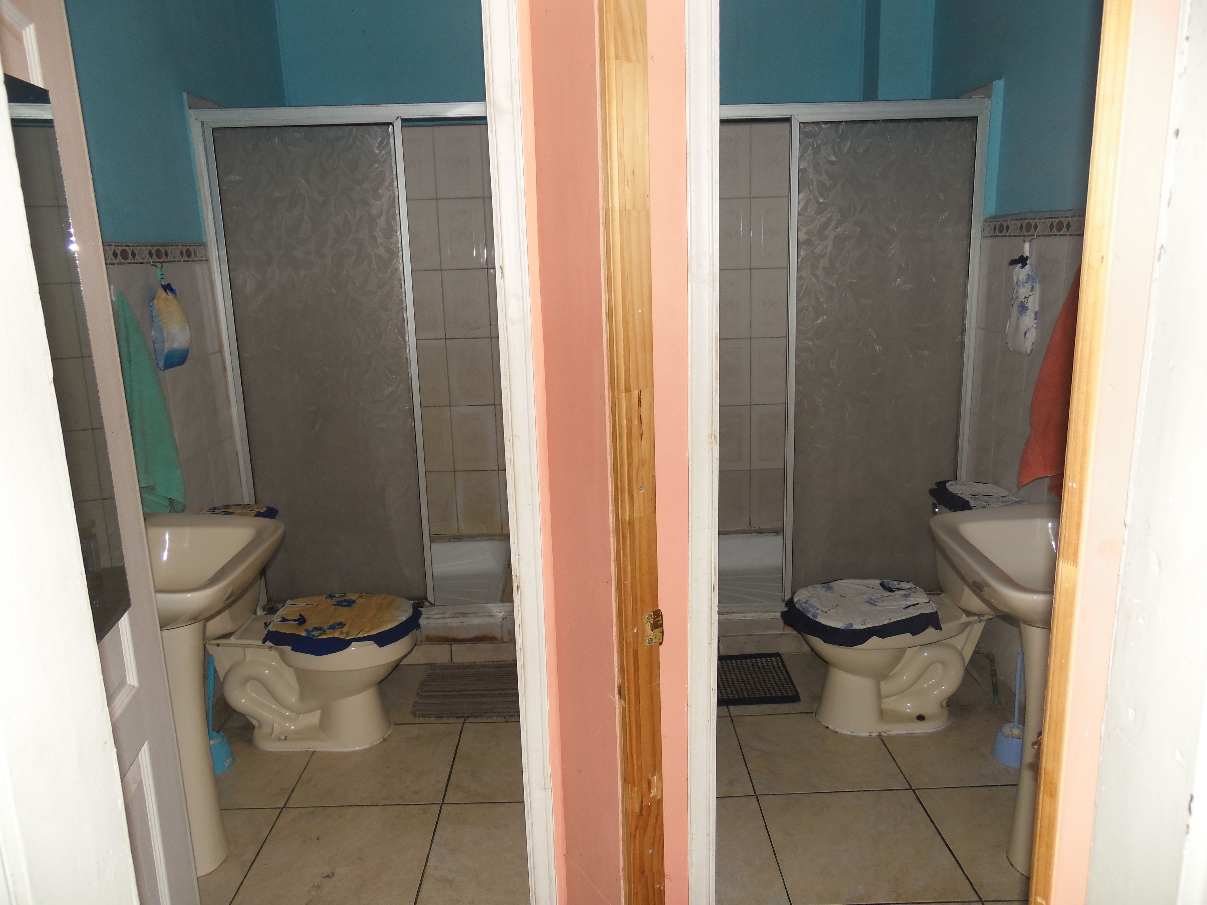 A bathroom with two toilets, a shower, and a sink.