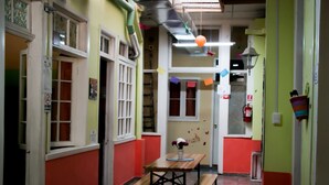 Un pasillo estrecho con una mesa, bancos, un extintor y una puerta con ventanal.