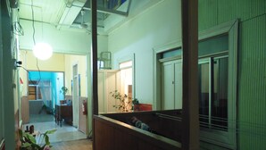 Un pasillo estrecho con suelo de madera, un ventilador de techo y una planta en maceta.