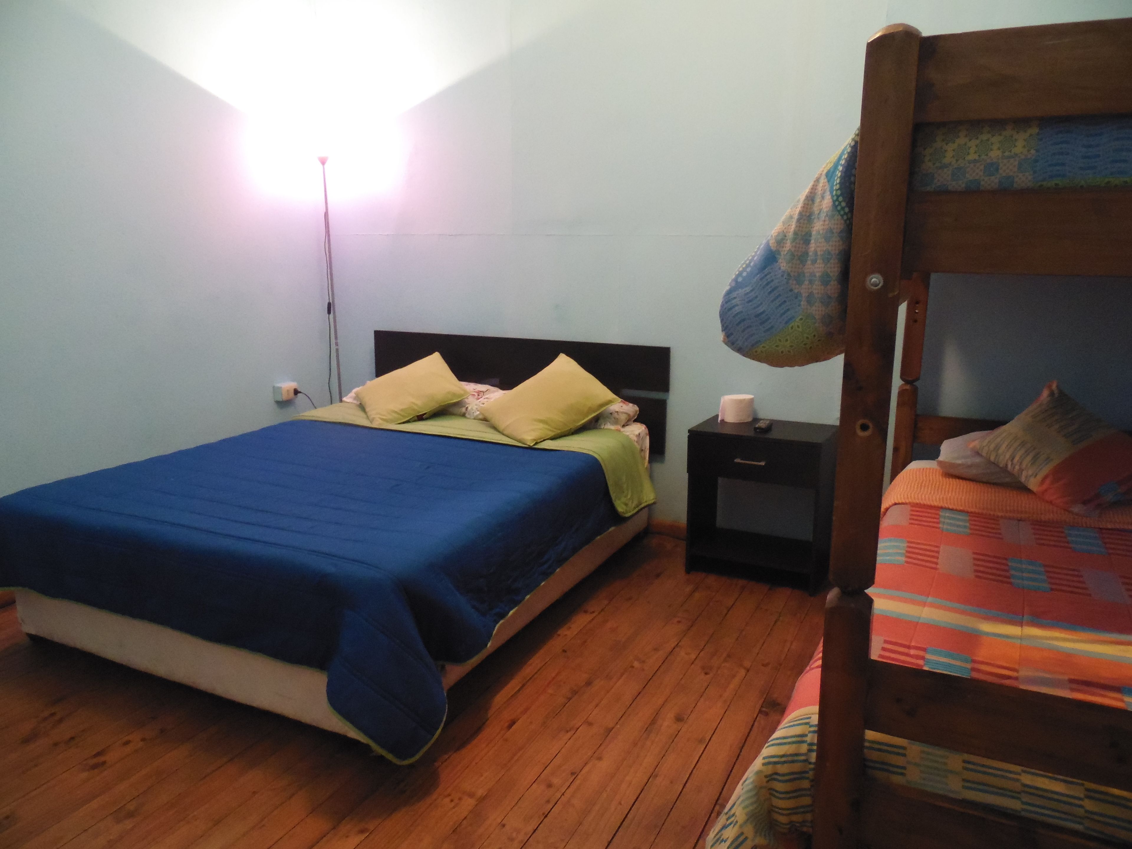 A room with a bunk bed, a single bed, a nightstand, and a bedside table.
