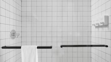 A modern bathroom with white tiled walls, a black shower enclosure, and a white towel hanging on a black towel bar.