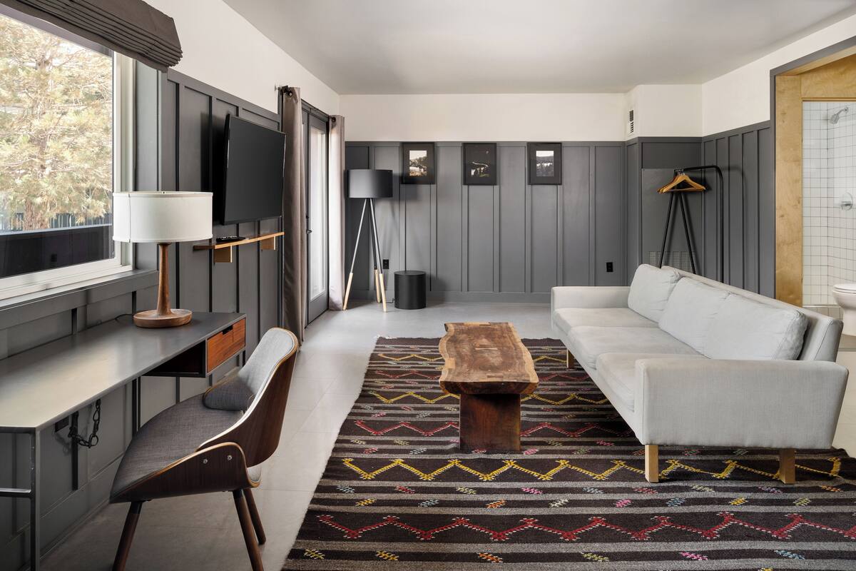 Un salon moderne comprenant un canapé, une table basse, un téléviseur et un bureau avec une lampe.