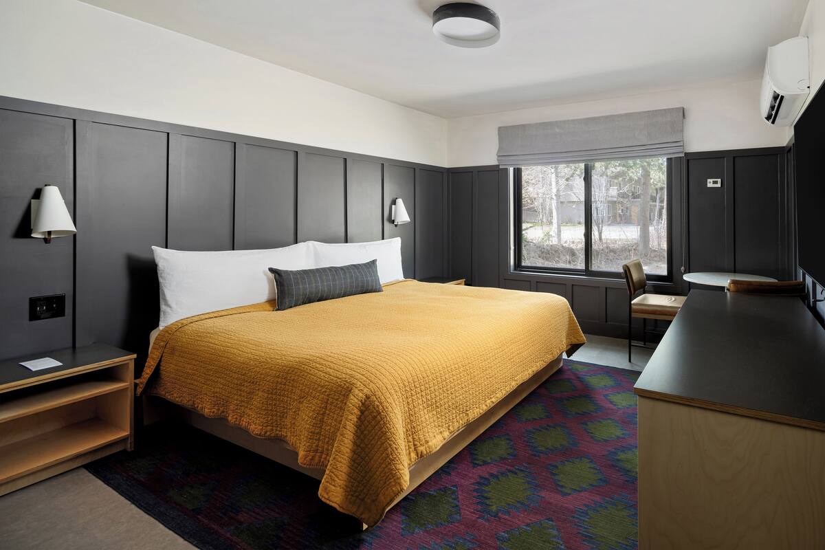 Une chambre d’hôtel moderne, dotée d’un grand lit, d’un bureau et d’une fenêtre offrant une vue agréable.