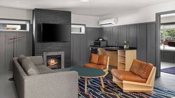 Una sala moderna con chimenea, televisor de pantalla plana, muebles de cuero y una zona de cocina con microondas y fregadero.