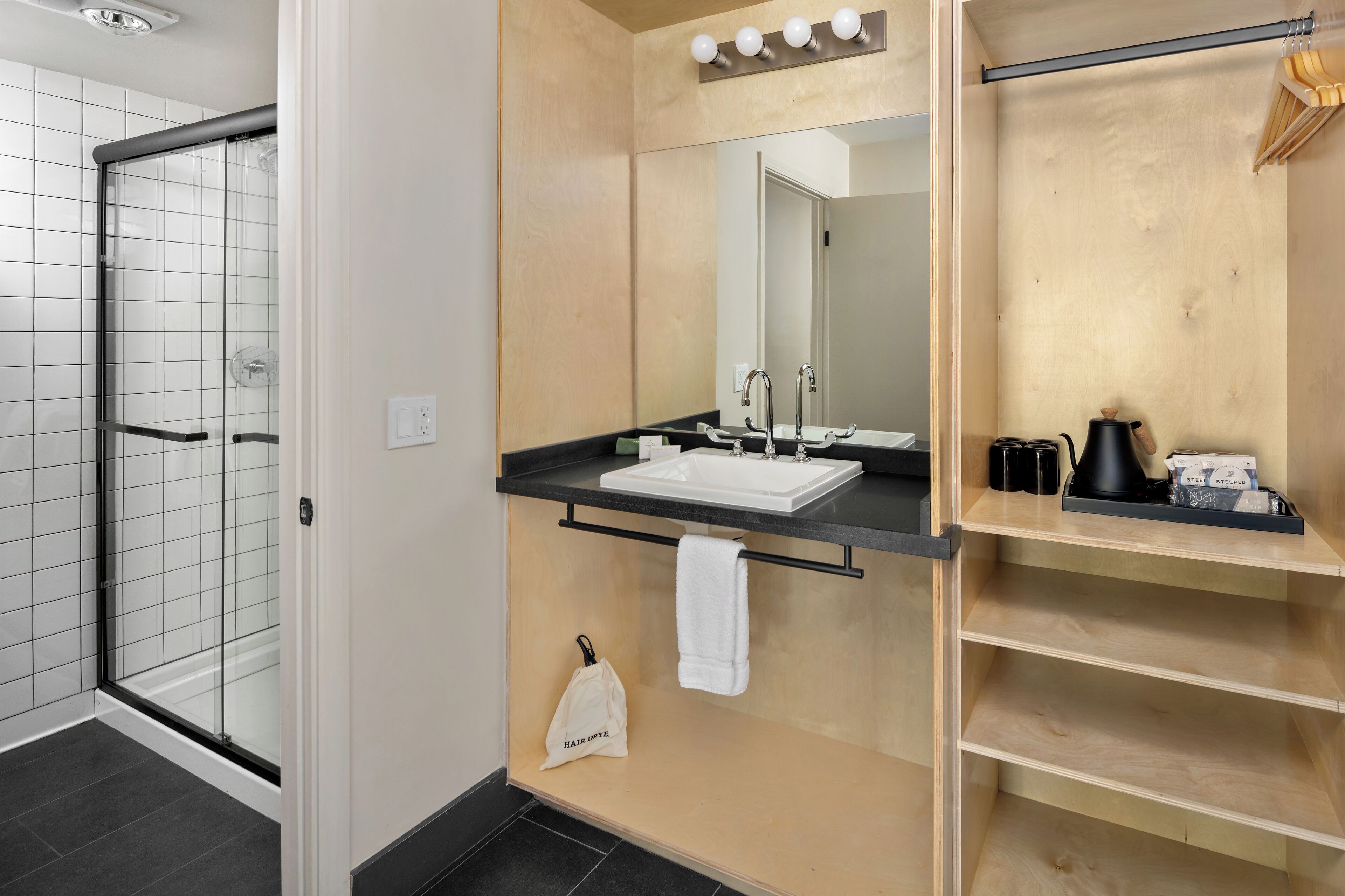 A modern bathroom with a glass shower, a sink with a mirror, and a shelf with toiletries.