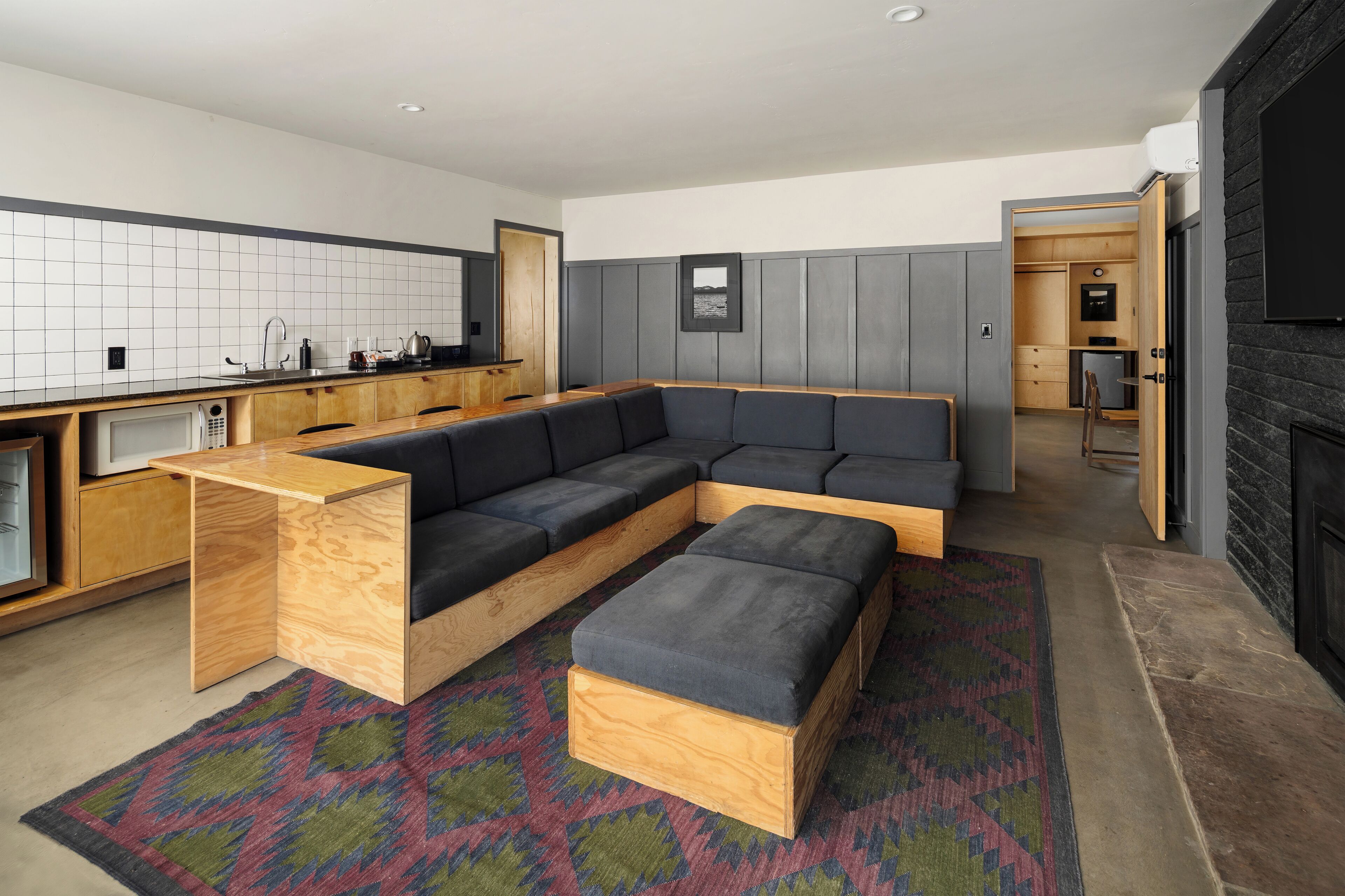 A modern kitchen with a built-in wooden bench and a large sectional sofa.