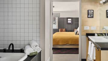 A hotel bathroom with a large bathtub, a sink, and a mirror.