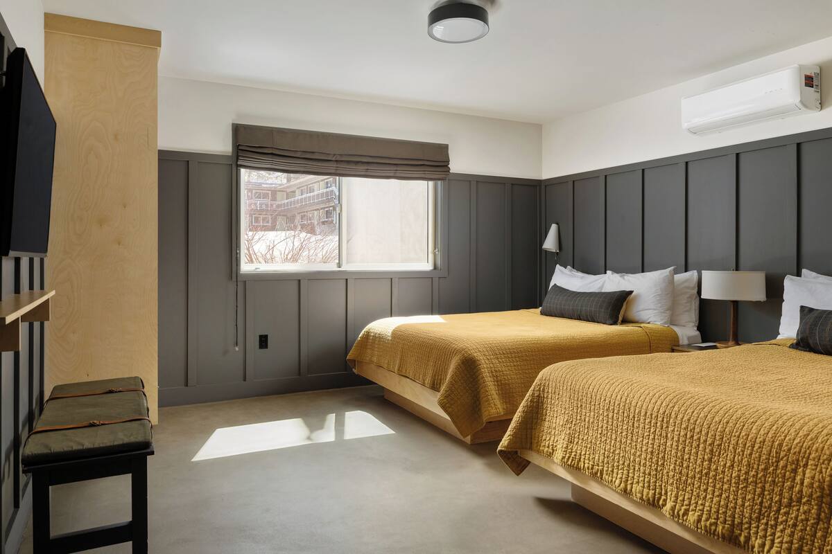Une chambre d’hôtel avec deux lits, une fenêtre, un bureau et une chaise.