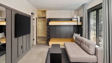 Una habitación de hotel moderna con una cama nido, un sofá, un televisor de pantalla plana y un ventanal con cortinas.