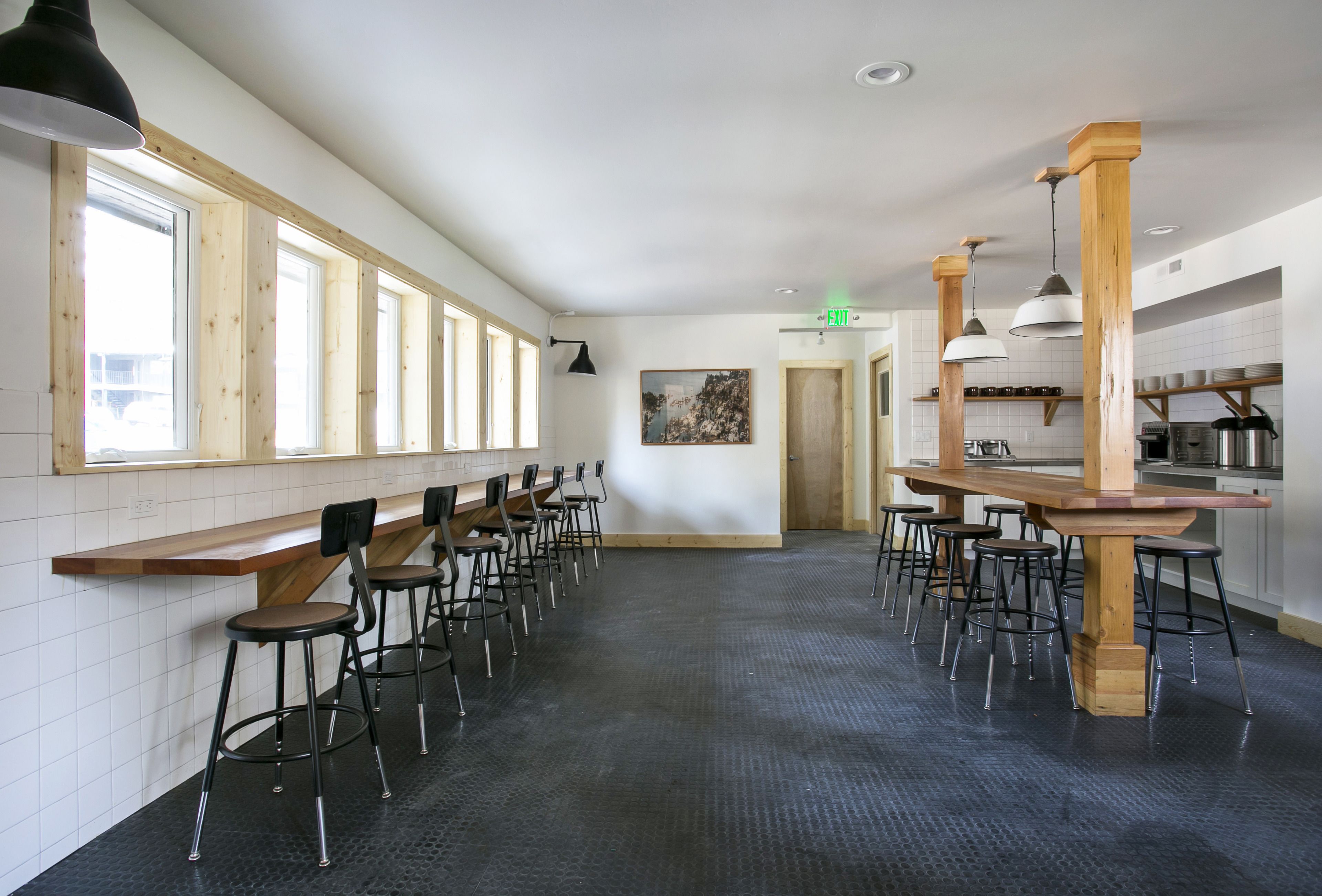 A spacious kitchen area with wooden bar stools and a long counter.