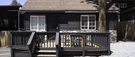 A two-story house with a wooden deck and a stone wall.