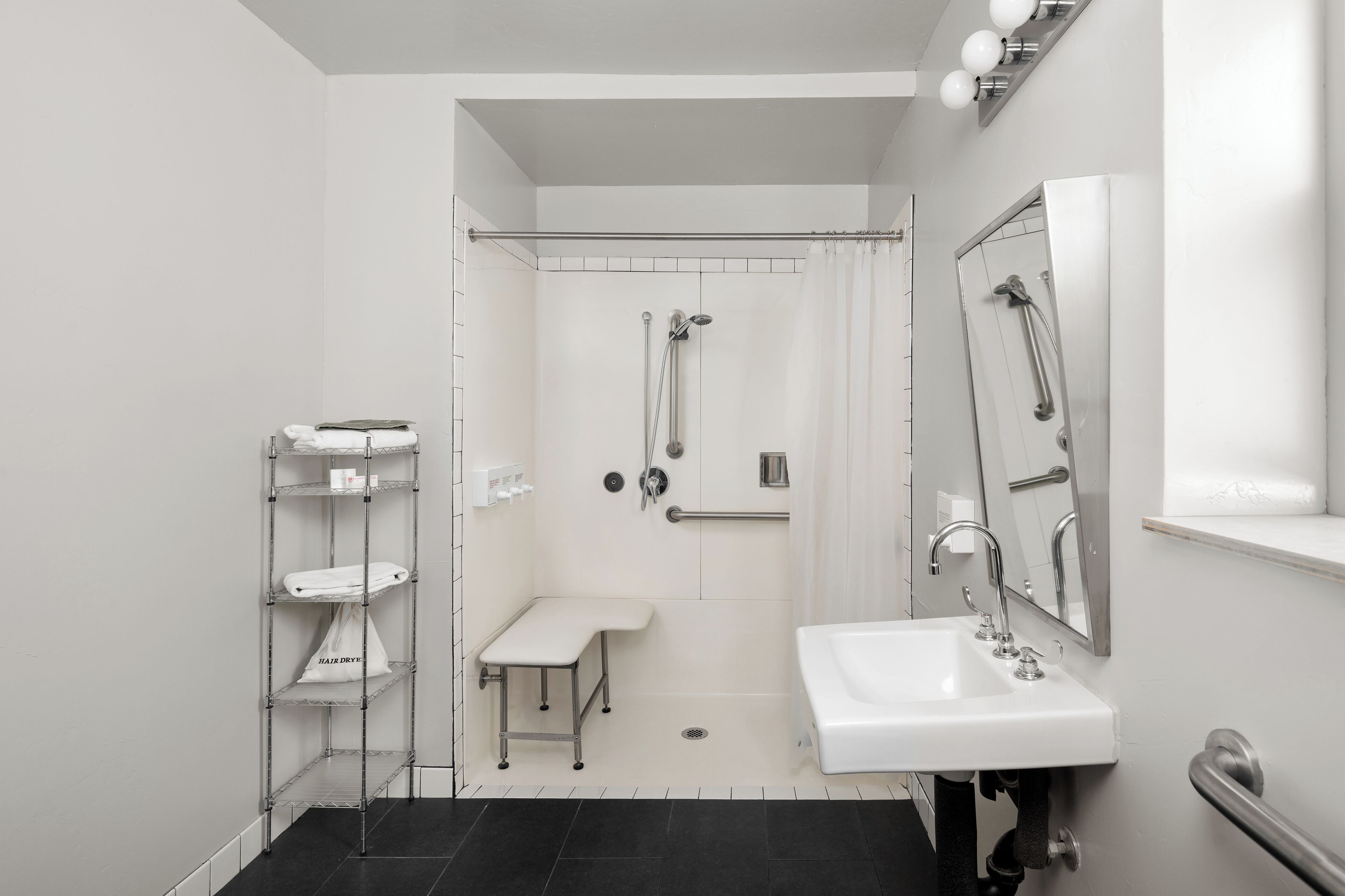 A modern bathroom with a shower, a sink, and a bench.