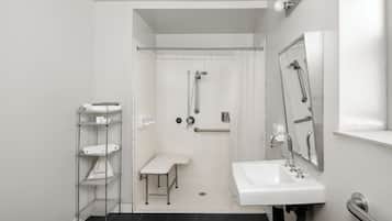 A modern bathroom with a shower, a sink, and a bench.