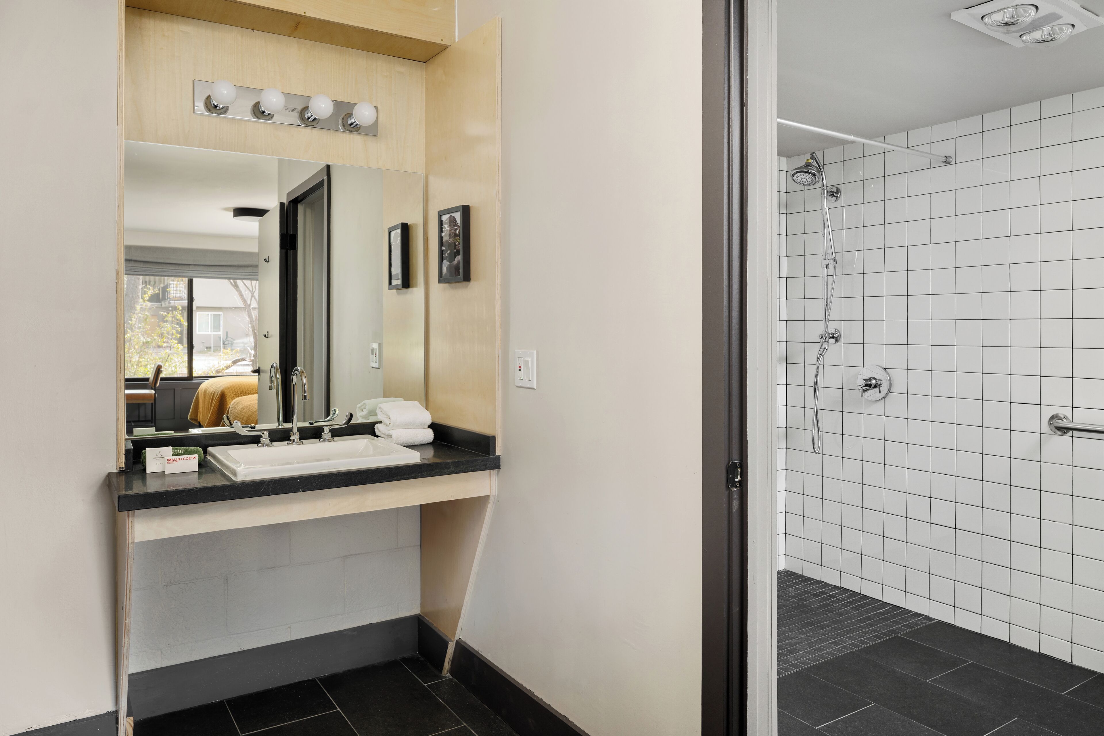 A modern bathroom with a sink, mirror, and shower.
