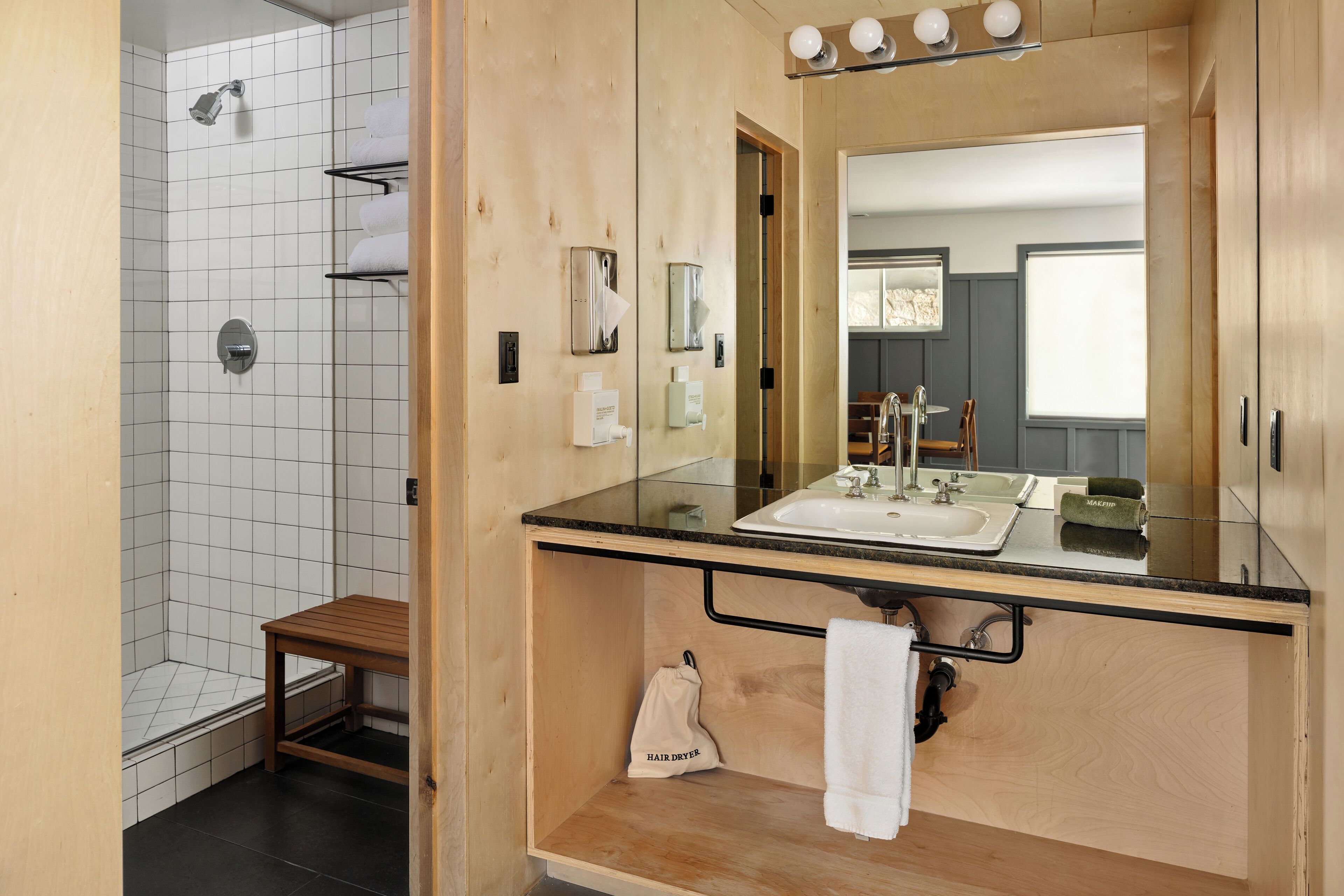 A modern bathroom with a glass shower enclosure, a wooden vanity with a sink, and a mirror above the vanity.