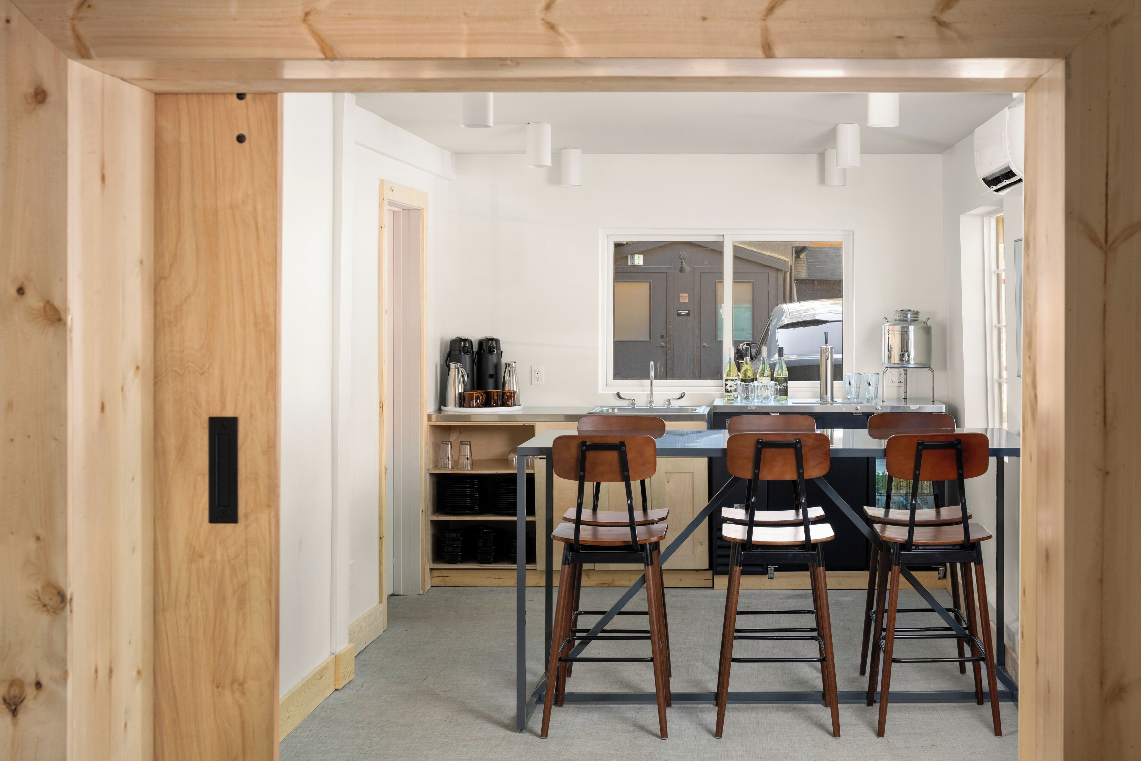 A modern kitchen with a central island, bar stools, and a view into the adjacent room.