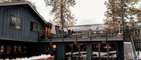 A modern building with a deck, outdoor seating, and a fire pit.