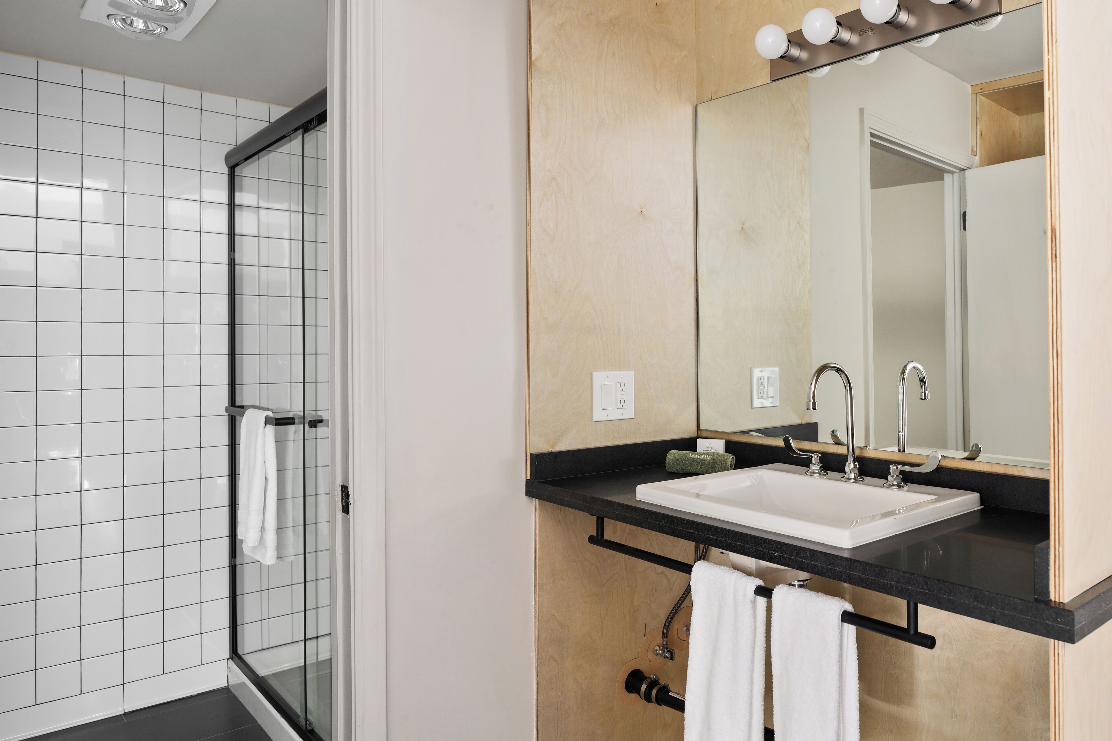 A modern bathroom with a glass shower enclosure, a black countertop sink, and a large mirror.
