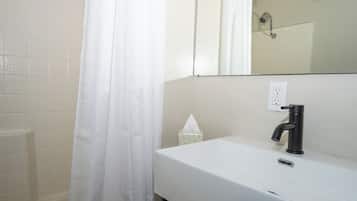 A bathroom with a white sink, a black faucet, a mirror, and a shower curtain.