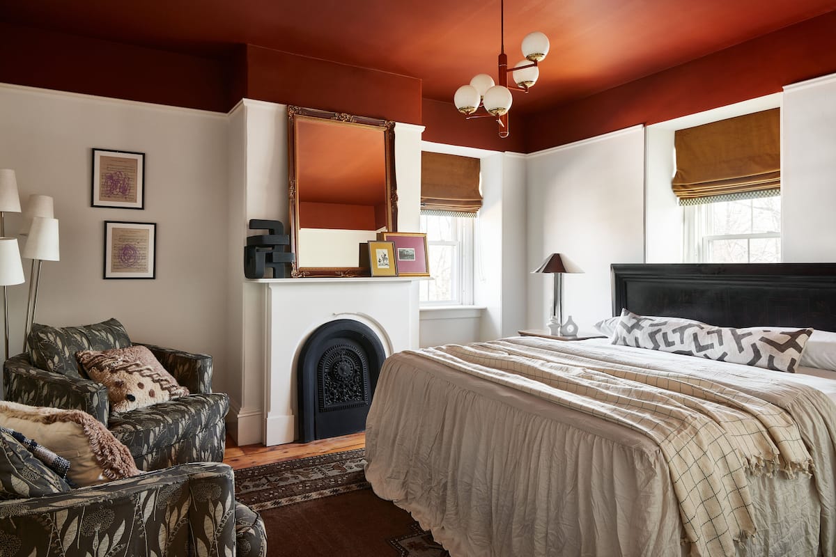 Quarto com uma cama grande, lareira, espelho e janela com vista.