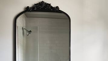 A bathroom with a white sink, a large mirror, and a shower.