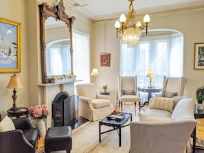 A well-lit living room with a fireplace, comfortable seating, and a large mirror. - Blind Tiger Portland – Carleton Street (Portland)