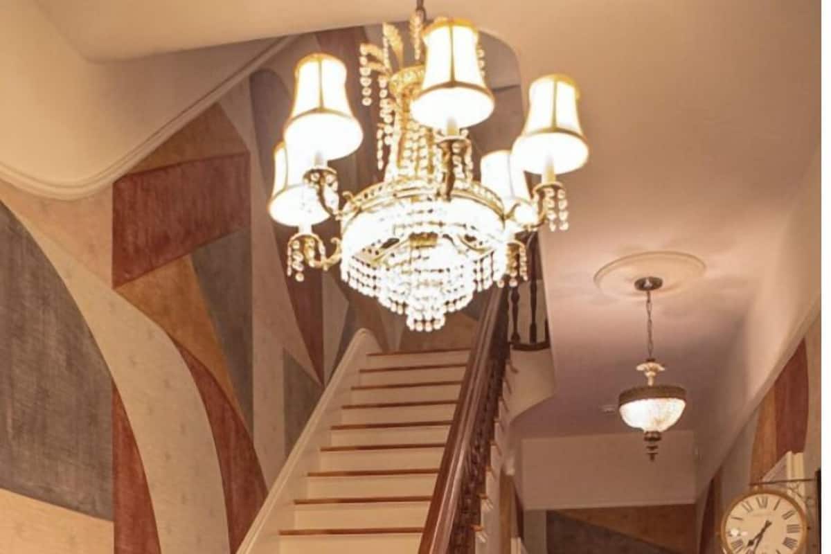 Uma escadaria com corrimão de madeira e um candelabro.