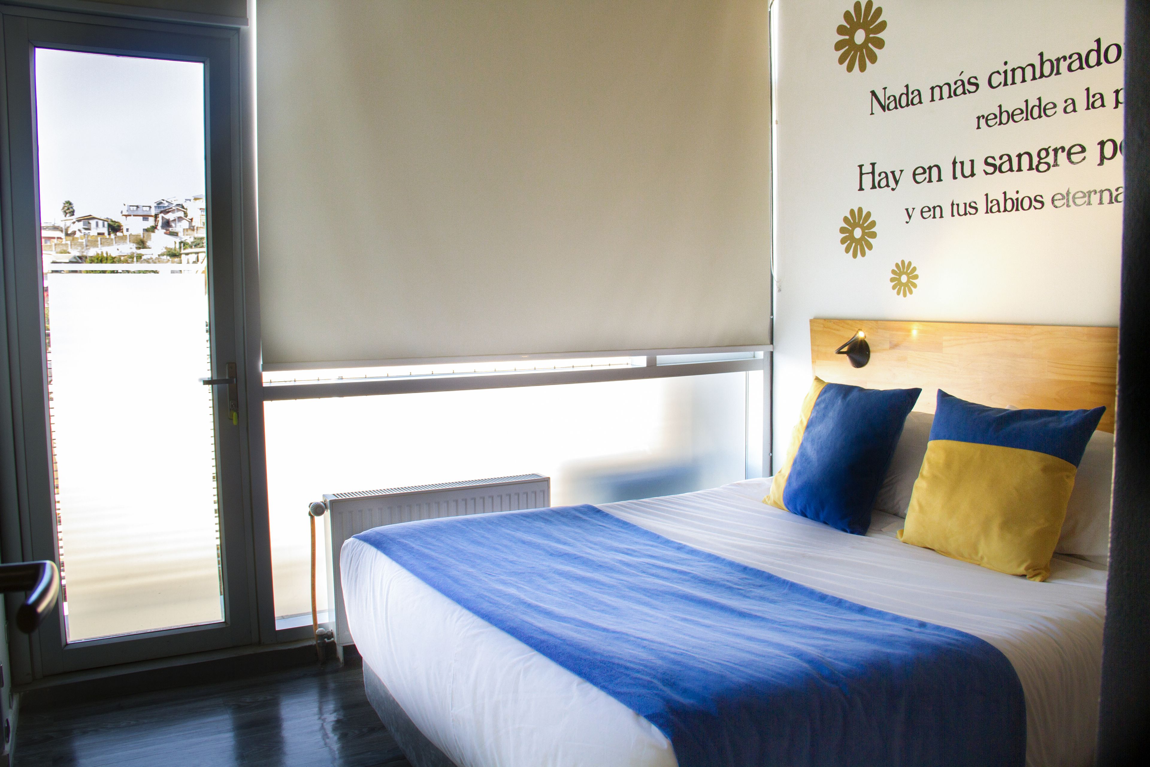 A hotel room with a bed, a window, and a wall with text.