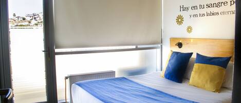 A hotel room with a bed, a window, and a wall with text.