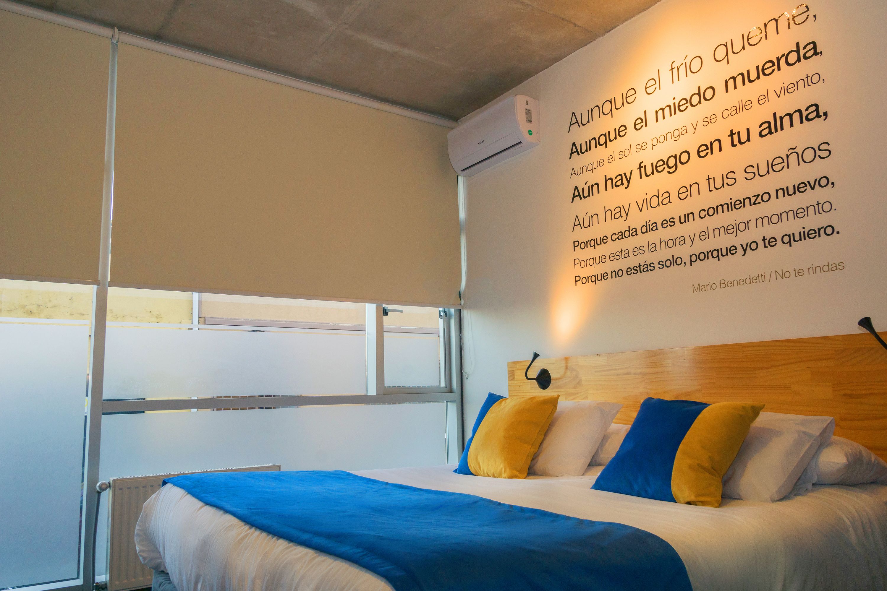 Ein Hotelzimmer mit Bett, Fenster und einer Wand mit Text.