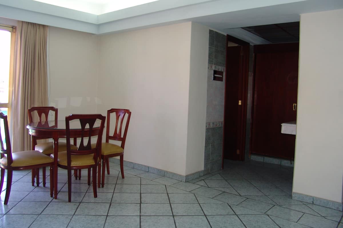 Ein Essbereich mit einem runden Tisch und vier Stühlen, einem gefliesten Boden und einer Tür zu einem Badezimmer.