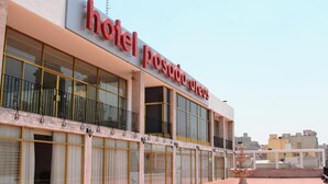 Un hotel con un gran letrero que dice "hotel posada arcos" y una fuente en el patio.