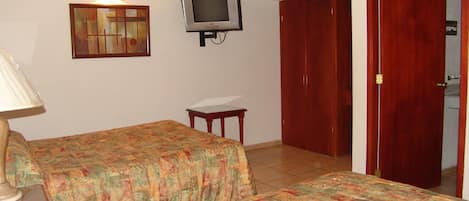 A room with two beds, a television, a painting, and a wooden wardrobe.