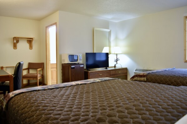 A hotel room with two beds, a desk with a chair, a television, a lamp, and a mirror. - The Otter Supper Club & Lodge (Ottertail)