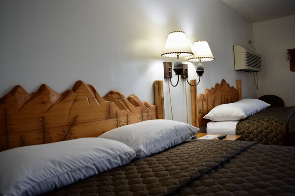 A hotel room with a wooden headboard, two wall-mounted lamps, a bed with white and brown bedding, and an air conditioning unit on the wall. - The Otter Supper Club & Lodge (Ottertail)