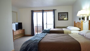 Habitación de hotel con dos camas, un televisor en una cómoda, un balcón con cortinas y un cuadro en la pared.