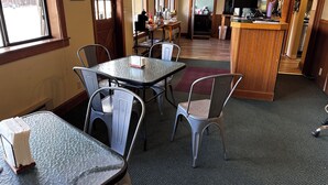 A restaurant with a bar area, tables, and chairs.
