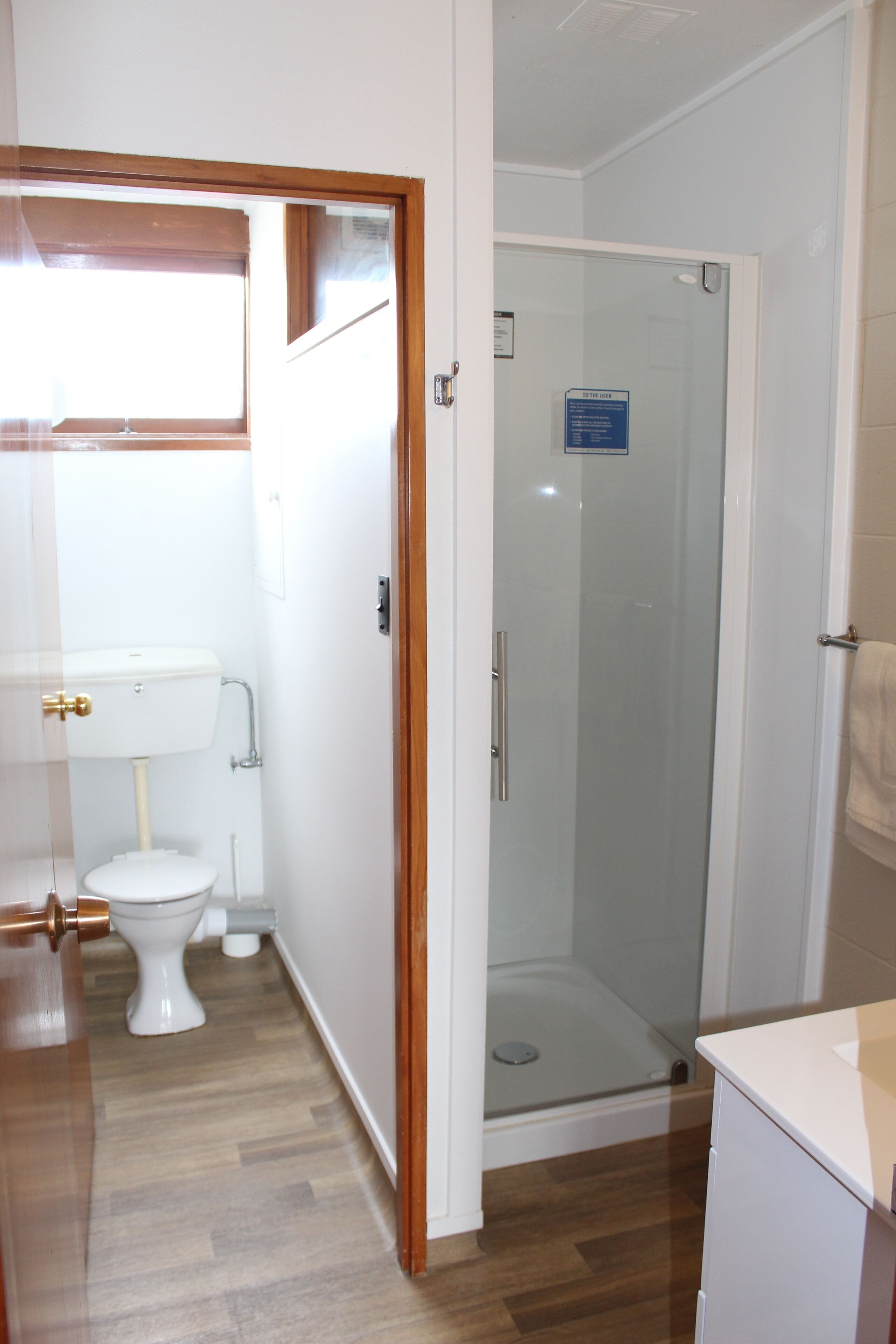 A bathroom with a toilet, a glass shower enclosure, and a sink.