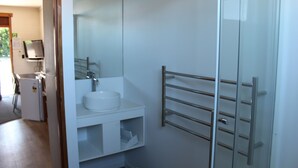 A modern bathroom with a glass shower enclosure, a white sink, and a metal towel rack. - Elmore Lodge Motel (Hastings)