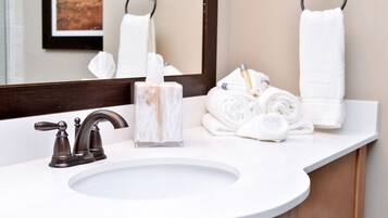 A bathroom with a white sink, dark-toned faucet, and a marble soap dispenser.