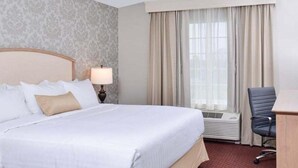 A hotel room with a large bed, a desk, and a window with curtains. - Appomattox Inn and Suites (Appomattox)