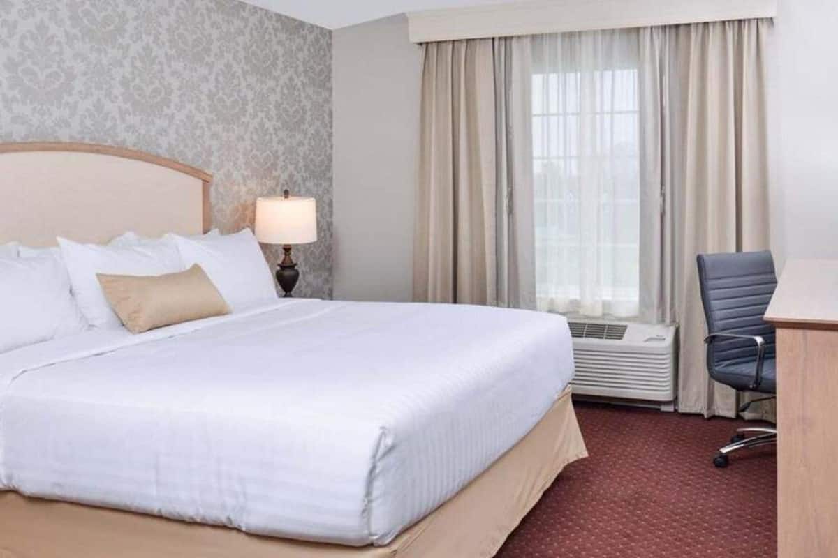 Una habitación de hotel con una cama grande, un escritorio y una ventana con cortinas.
