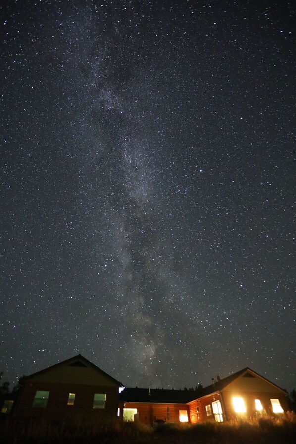 Ein Haus, über dem der Himmel in einer sternenklaren Nacht die Milchstraße sichtbar ist.