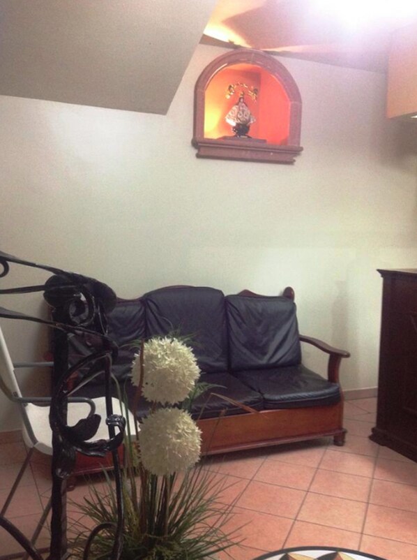 Una sala de estar con un sofá de cuero negro, una mesa de centro de madera y una planta en maceta.