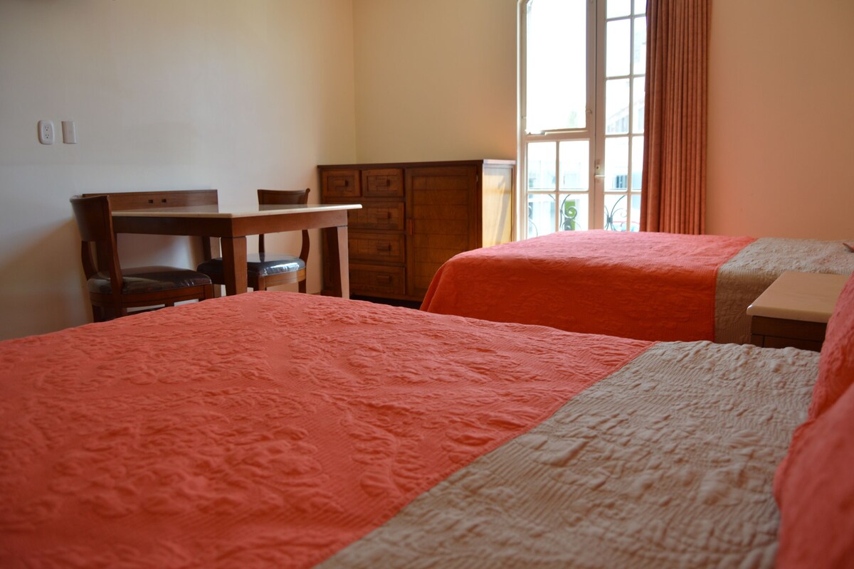 Une chambre avec deux lits, un bureau et une commode.